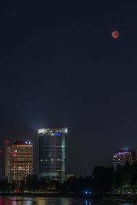 Illuminated buildings in city against sky at night