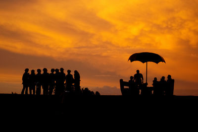 A group of people posing for a photo during the dark hour of sunset