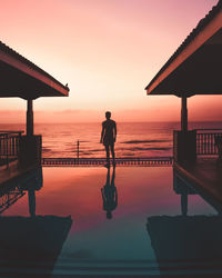 Silhouette man looking at sea against sky during sunset