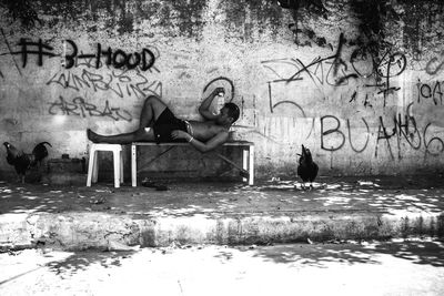 Woman sitting by graffiti on water