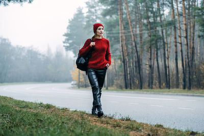 Alone woman with backpack near road on forest background. hipster girl wanderlust walking on