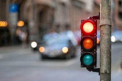 City crossing with a semaphore on blurred background with cars in the evening streets, red light