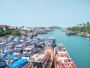 Boats moored at harbor against clear sky