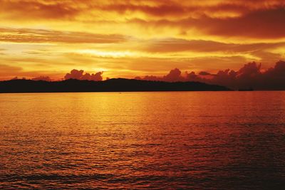 Scenic view of sea against dramatic sky during sunset