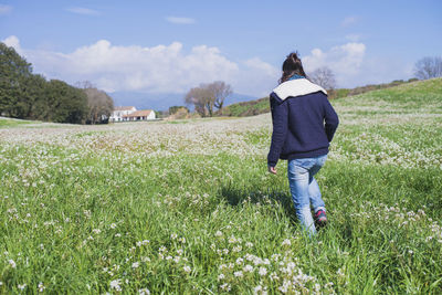 Rear view of woman standing on field against sky