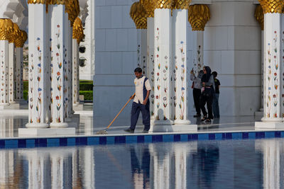 People standing by swimming pool against building