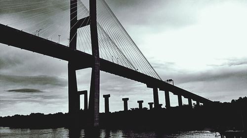 Low angle view of bridge against cloudy sky