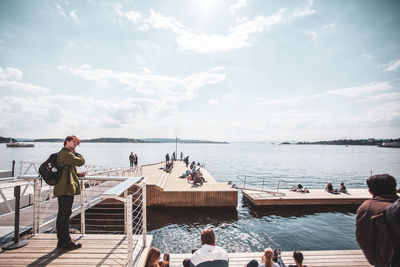 People looking at sea against sky