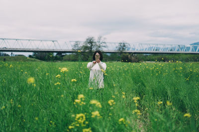 Woman on grassy field against cloudy sky