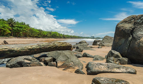 Scenic view of rocks by sea against sky