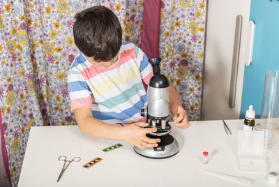 Little child caucasian boy looking through microscope in school.