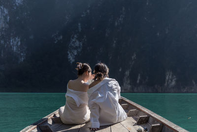 Rear view of couple sitting by lake