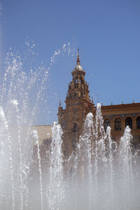 Fountain in front of building against clear sky