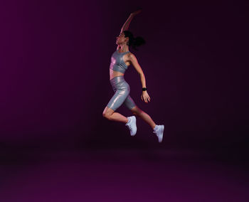 Full length of woman jumping against black background