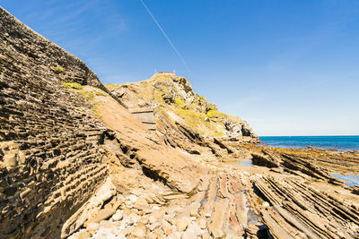 Scenic view of rocky beach against blue sky