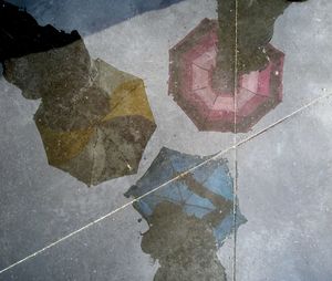 Reflection of people with umbrellas on road