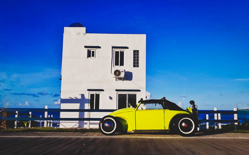 Yellow car on road against blue sky