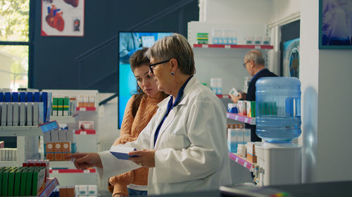 Young woman using mobile phone while standing in laboratory