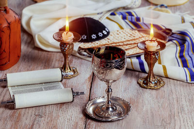 High angle view of matzo with drink and candles on wooden table against wall