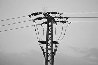 Low angle view of silhouette electricity pylon against sky