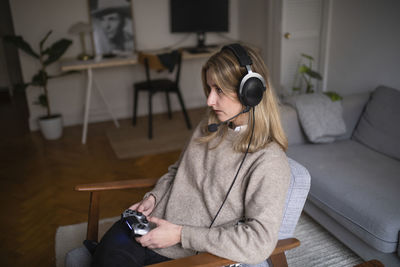 Woman using mobile phone while sitting on sofa at home