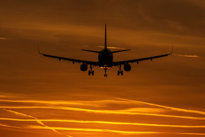 Low angle view of silhouette airplane against sky during sunset