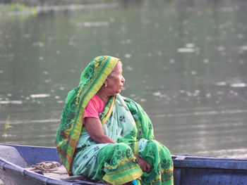 Side view of woman sitting on boat over river 