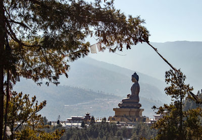 Statue amidst trees and buildings against sky
