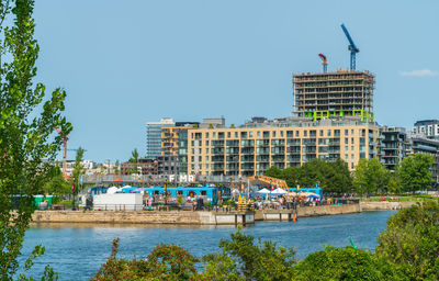 Buildings by river against clear blue sky