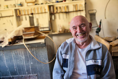 Portrait of an old happy violin maker in his workshop. person