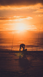 Silhouette man fishing on sea against sky during sunset