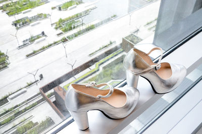 High angle view of silver high heels on window sill