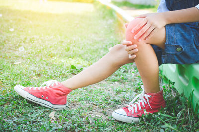 Low section of girl holding knee while sitting at park