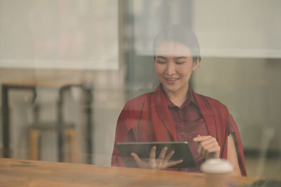 Portrait of smiling young man using phone on table