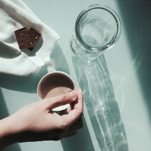 High angle view of hand holding spoon in coffee at table