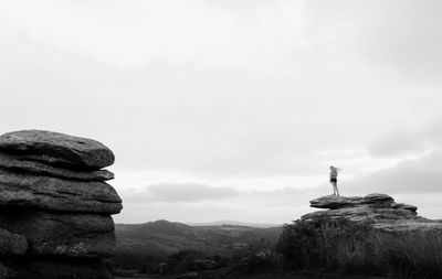 Scenic view of rock and one person silhouette  against sky