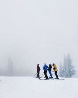 People skiing on hill in foggy weather