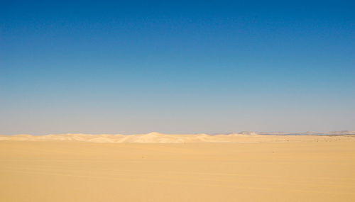 Scenic view of desert against clear blue sky