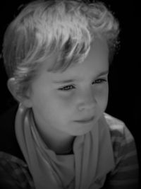 Close-up of thoughtful boy against black background