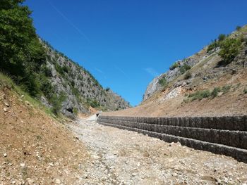 Road by mountain against clear blue sky