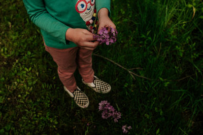 Faceless image of young girl playing with purple flowers