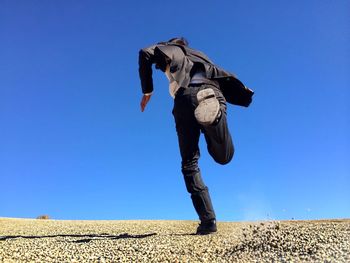 Low angle view of woman against clear blue sky