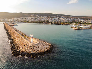 Lighthouse on the stone breakwater at harbor mouth aerial view.