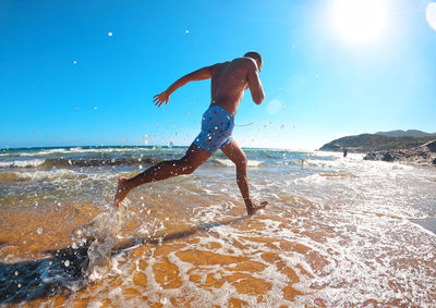 Man surfing in sea against sky on sunny day