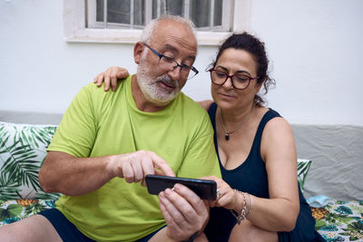 Young man using smart phone while sitting on laptop