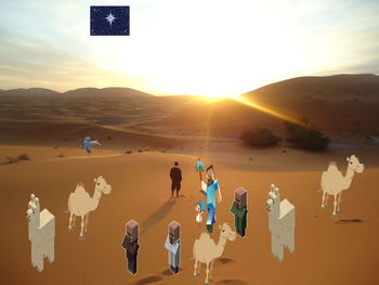 People enjoying in desert against sky during sunset