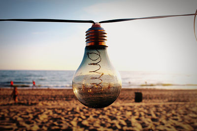 Close-up of light bulb hanging on beach