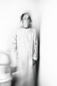 Blurred motion of woman standing against white background