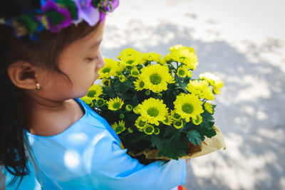 Close-up of girl holding yellow flowers