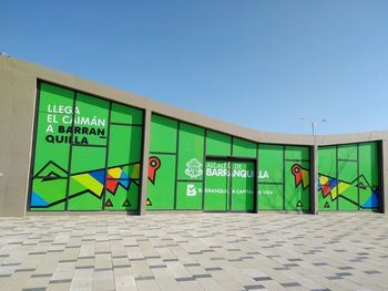 Information sign on wall by street against clear blue sky